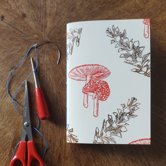 Notebook with linoprinted cover featuring fungi & pine cones
