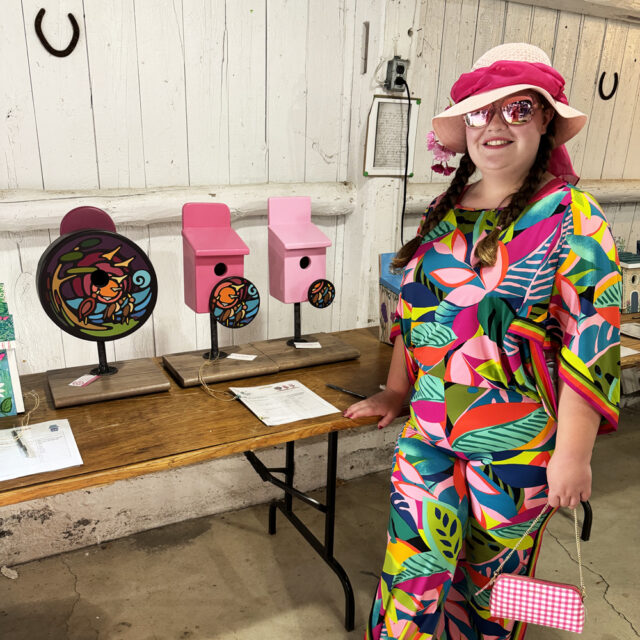 Po standing with her painted bird box triptych created for the SSJI fundraiser - 2024